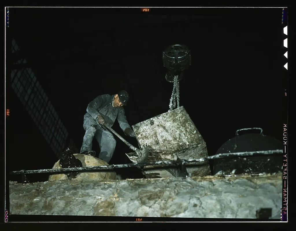 A railway shop worker spreading a wet asbestos insulating mixture over a locomotive boiler, 1942