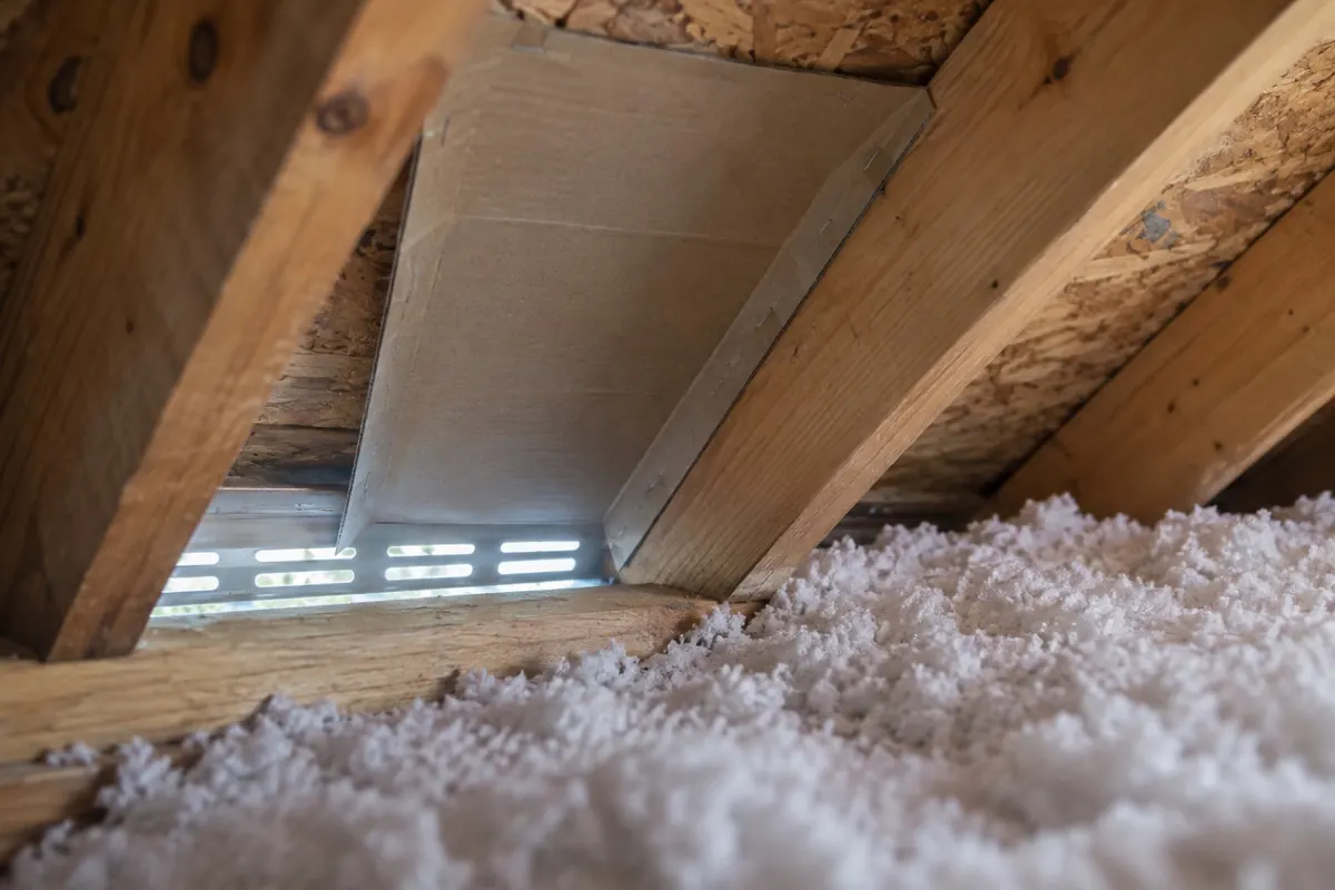 Illustration: a rafter baffle keeping insulation clear of a soffit vent at the attic eave