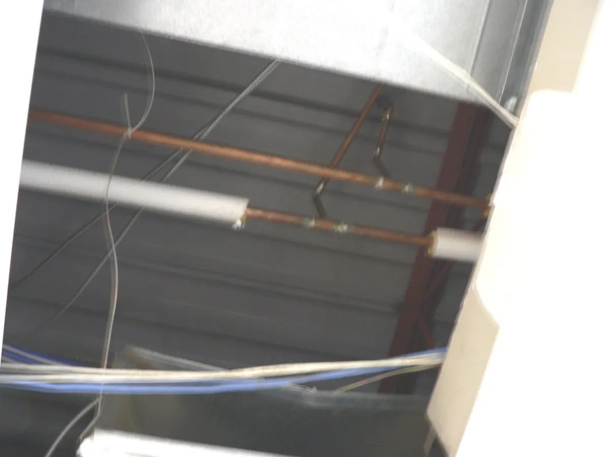 Copper pipes above a ceiling, some covered with white jacketed fiberglass insulation and some bare