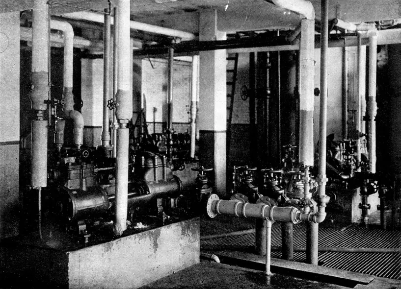 A 1921 photograph of an oil refinery pump room with pipes covered in thick white insulation