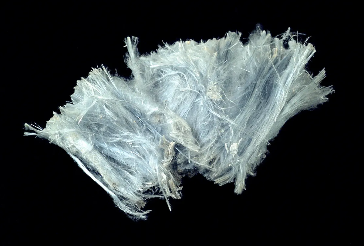 A loose tuft of pale blue grey fibres, a crocidolite hand specimen photographed on a black background