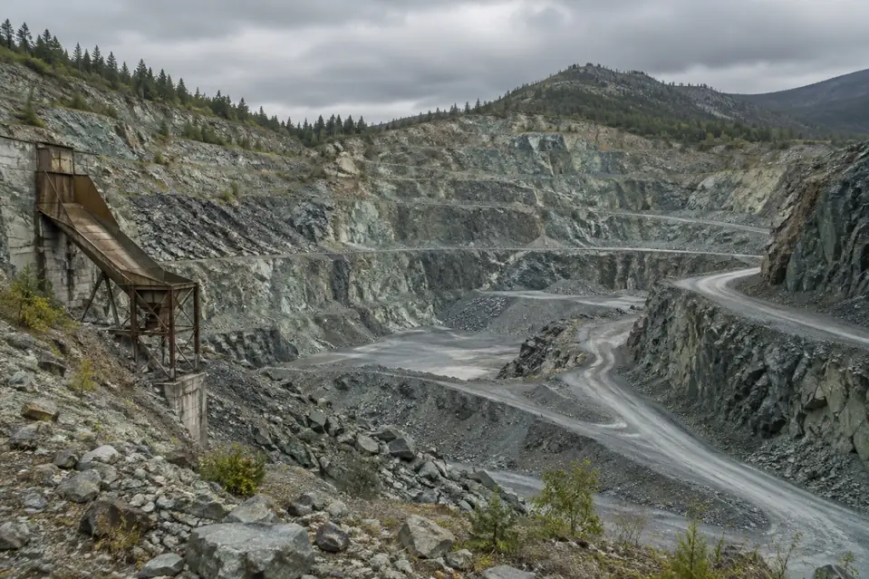 Illustration: a disused open pit quarry in serpentine hills, standing in for a historic mine site, not a reference image of any mineral